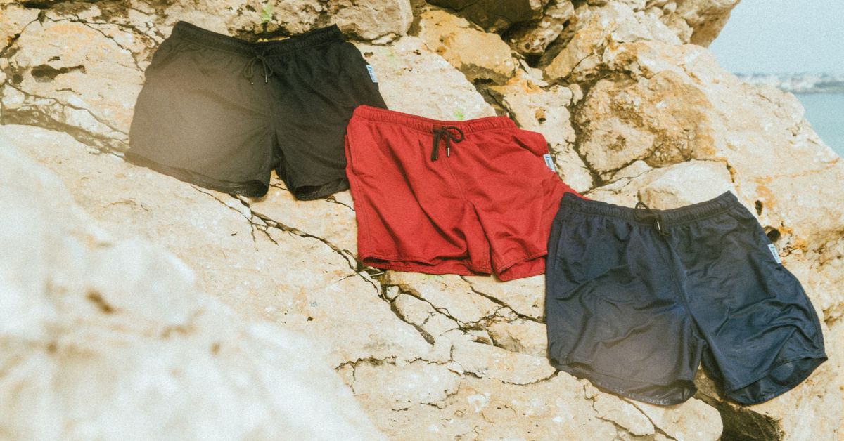 Rote Badehose, blaue Badehose und schwarze Badehosen trocknen auf den Felsen.