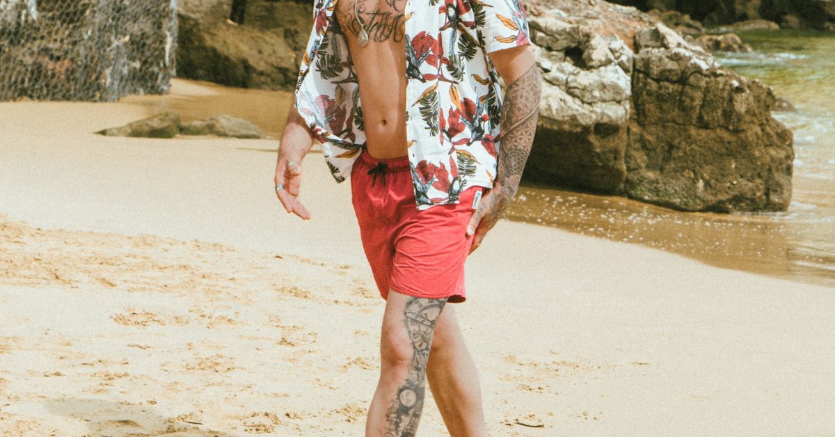 Guy walking on the beach wearing swimming trunks