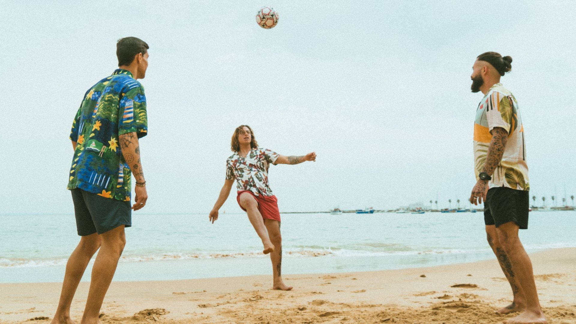 Load video: Video of guys playing football and skateboarding, summer vibes! They are showing of the sustainable swim shorts